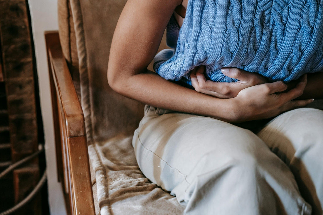 Close-up of woman clutching abdomen, a common sign of chronic pain conditions.
